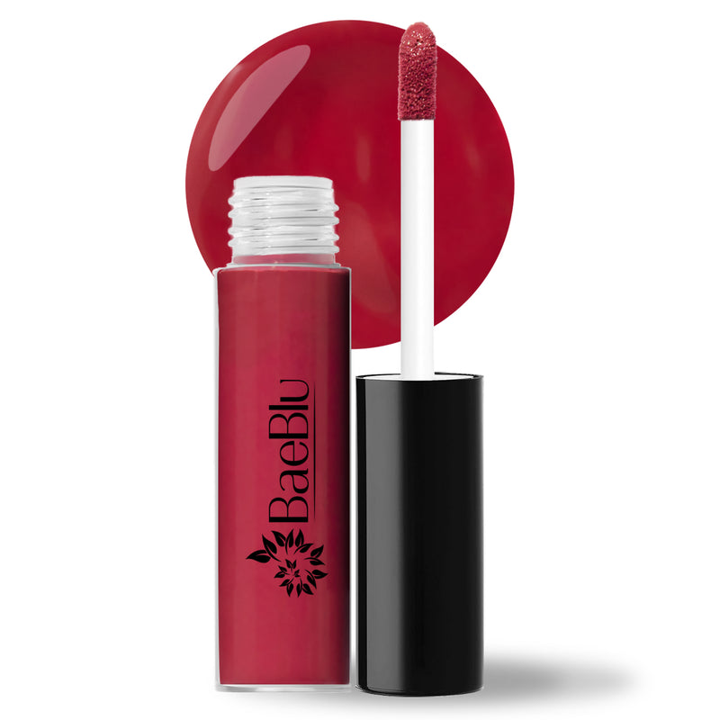 BaeBlu liquid gloss in the color Camellia, with the applicator open and stood next to the bottle, and the shade of the gloss illuminated behind the open bottle in a circular shape. 